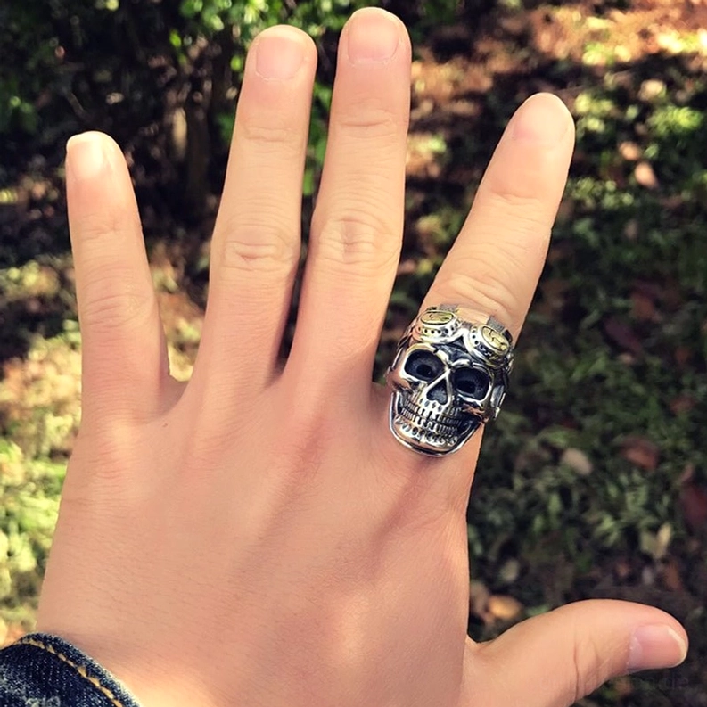 Aviator Totenkopf Ring an Hand getragen Mittelfinger Outdoor grüner Hintergrund Casual Wear Gothic Biker Schmuck