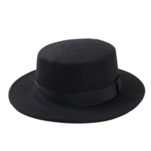 Schwarzer Flat Top Fedora aus Wollfilz mit strukturierter Flachkrone, fotografiert von vorne oben, zeigt architektonische Präzision der gotischen Hutform und schwarze Satin-Hutband-Details