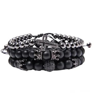 Schwarzes gotisches Mehrschicht Charm Armband mit mattem Naturstein Achat Perlen, verziertem Kreuzanhänger, Kronencharm und Lavagestein auf weißem Hintergrund, flache Produktfotografie
