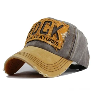 Verblasste gelb-graue Zwei-Ton-Denim-Gothic-Cap mit ausgefranstem Schirm und ROCK-Stickerei-Patch, Vorderansicht mit dreiviertelseitiger Perspektive