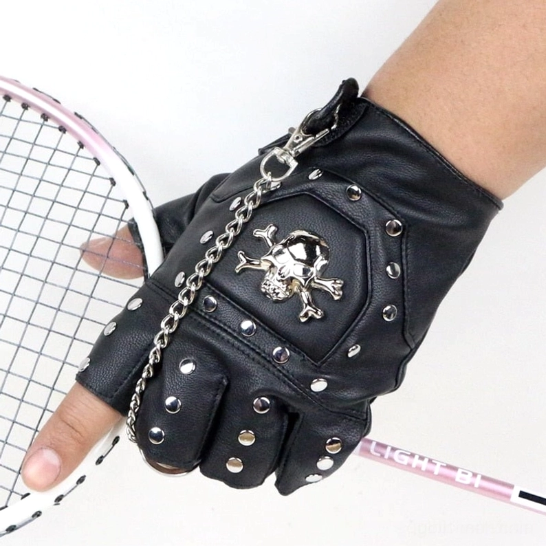 Schwarze Kunstleder Halbfingerhandschuhe getragen an Hand beim Badminton-Schlag, Seitenansicht mit Skull-Emblem und Kettendetail sichtbar