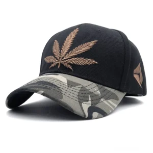 Schwarze Baseball Kappe mit brauner Hanfblatt-Stickerei und grauem Camouflage-Schirm, Vorderwinkel-Perspektive zeigt gotische Design-Details und rebellische Alternative-Streetwear-Ästhetik