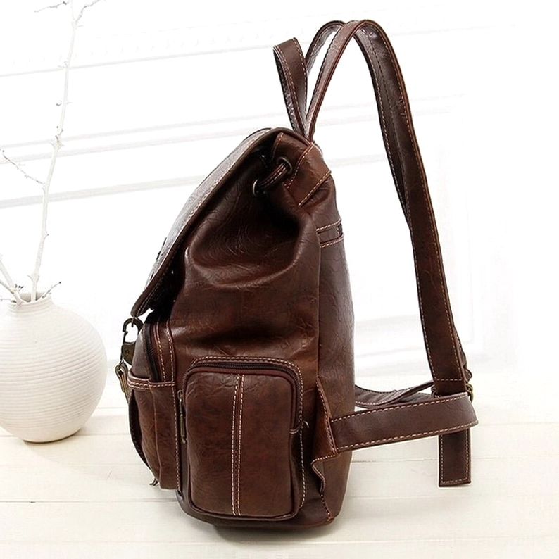 Dunkelbrauner Vintage-Rucksack in Drei-Viertel-Rückansicht mit sichtbarer genähter Seitentasche und gepolsterten Schulterriemen, Distressed-Leder-Finish und strukturelle Verarbeitungsdetails – Gothic Backpack Handwerkskunst