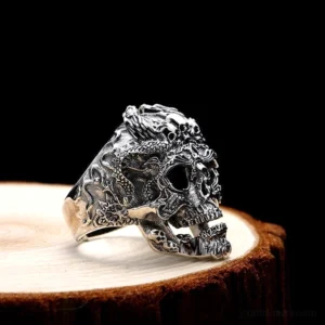 Biker Totenkopf Ring Seitenprofil mit detaillierten Reliefschnitzereien und Vintage-Patina auf Holzständer