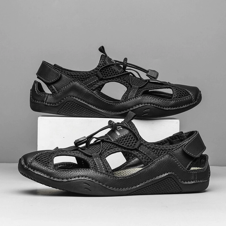 Herren Gothic schwarze Knöchel-Wrap Sandalen Überkopfansicht zwei Schuhe Display auf grauer Ausstellungsfläche
