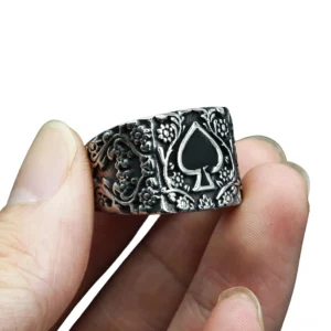 Vintage gotischer Spade Ring an Herrenfingern, Nahaufnahme Seitenansicht zeigt erhabene barocke Blütenmotive, schwarzes Spade-Wappentier, breites Metallband auf der Hand