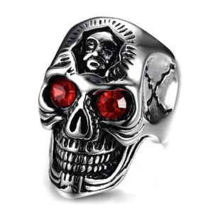Gotischer Totenkopfring mit roten Kristallaugen und aufwendiger Skelett-Gravur, Frontansicht zeigt Memento-Mori-Design mit Zinklegierung