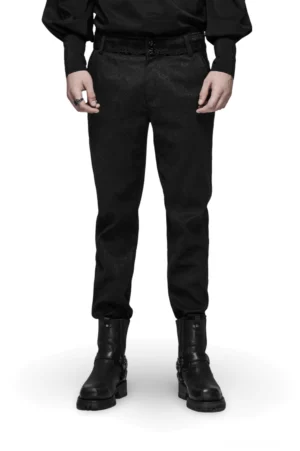 Schwarze Gothic Jacquard Slim-Fit Röhrenhose mit ornamentalem Metallverschluss, Frontansicht auf männlichem Model mit langer Behang und massiven Combat Boots