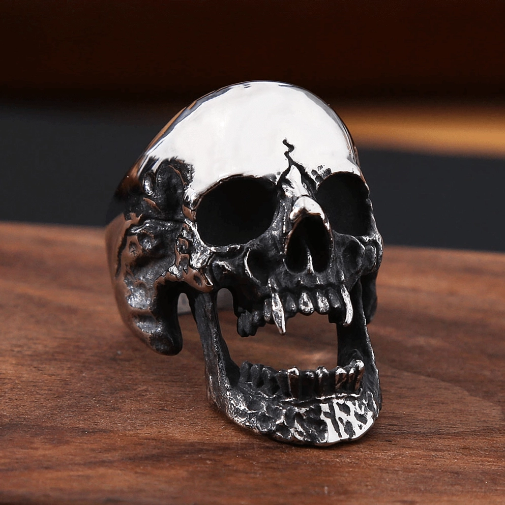 Vampire Skull Ring Dreiviertelvorderansicht zeigt strukturierte oxidierte schwarze Textur und hohles offenes Kieferdesign des gotischen Schmuckstücks auf Holzhintergrund